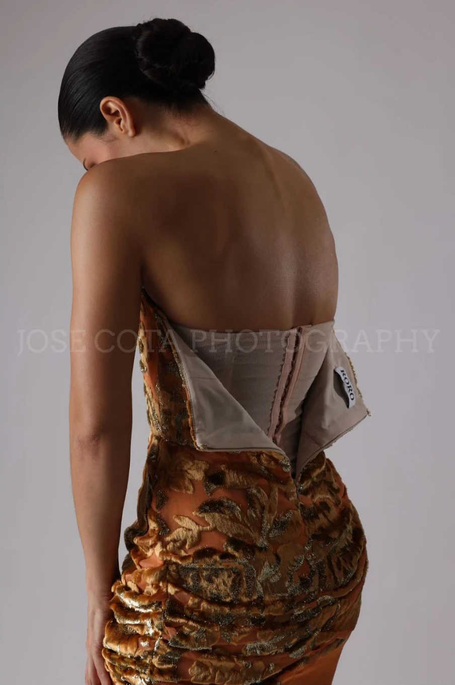 Espalda de The Lumiére Dress abierta, mostrando el corset interior bajo el brocado dorado